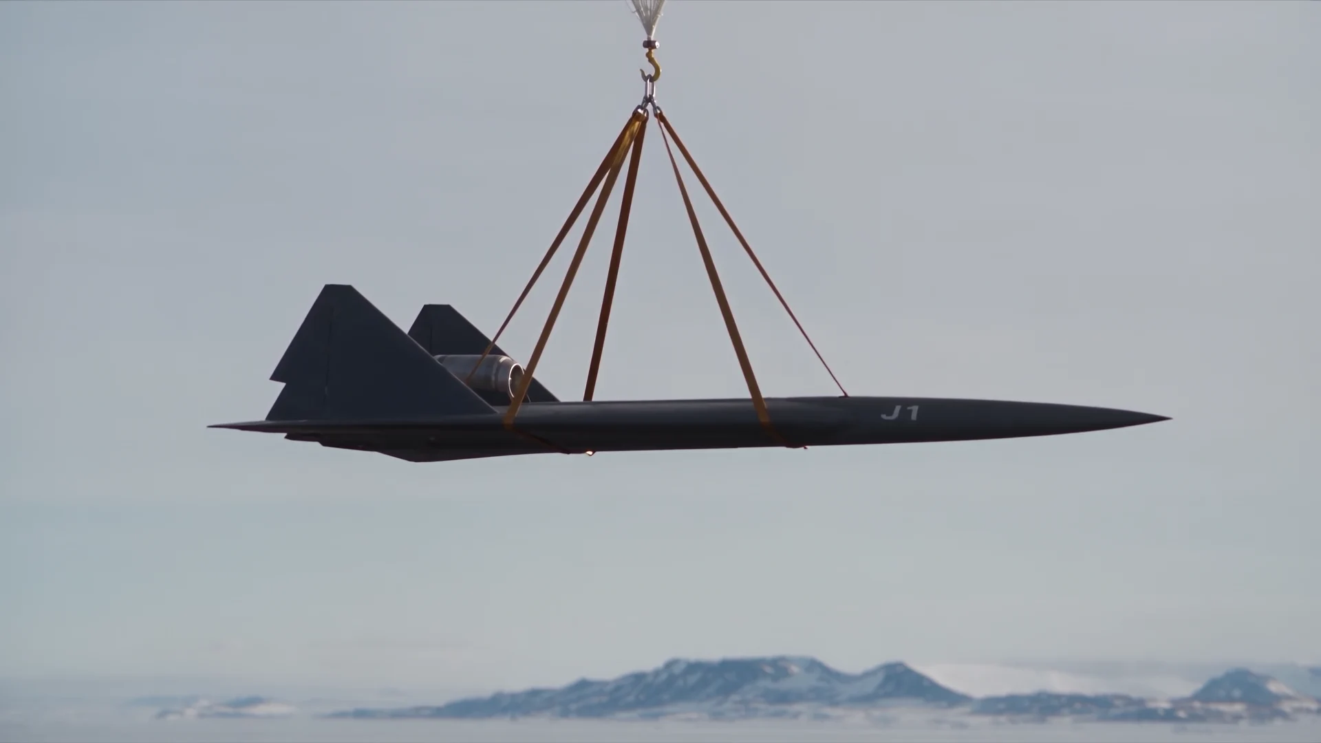 J1 suspended beneath balloon tethers above a distant landscape
